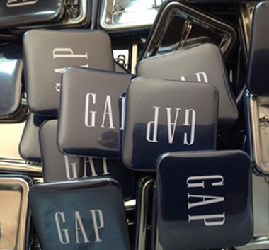 Varias Chapitas cuadradas con logo GAP en fondo azul